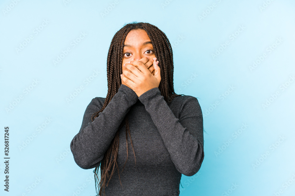 Young african american woman isolated on blue background shocked covering mouth with hands. Young african american woman isolated on blue background shocked covering mouth with hands.