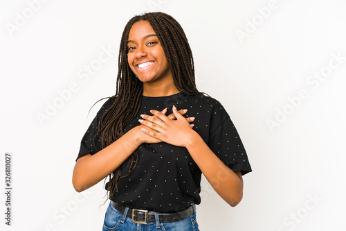 Young african american woman isolated on white background has friendly expression, pressing palm to chest. Love concept.