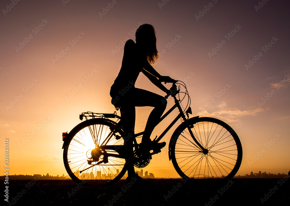 Obraz premium Girl on old bicycle at sunset