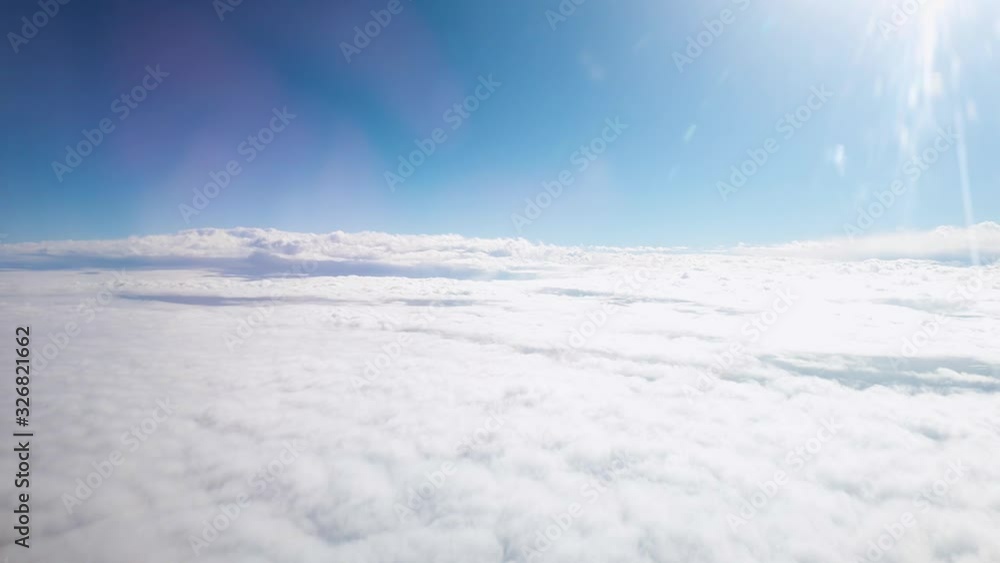 View throught the porthole on airplane flying above the clouds in clear blue sky View throught the porthole on airplane flying above the clouds in clear blue sky