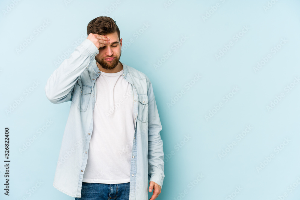 Fototapeta premium Young caucasian man isolated on blue background having a head ache, touching front of the face.