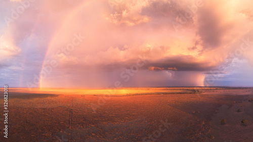 Stormy sunset with double rainbow  towering cumulus cloud and rain cells over a dry lake in Australia