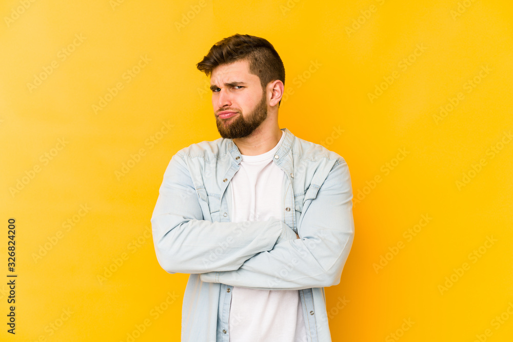 Young caucasian man isolated on yellow background suspicious, uncertain, examining you. Young caucasian man isolated on yellow background suspicious, uncertain, examining you.