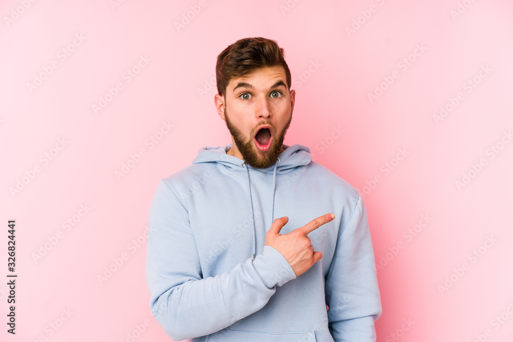 Young caucasian man isolated on pink background pointing to the side Young caucasian man isolated on pink background pointing to the side