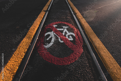 No Bike-riding sign on tracks in morning sunlight 