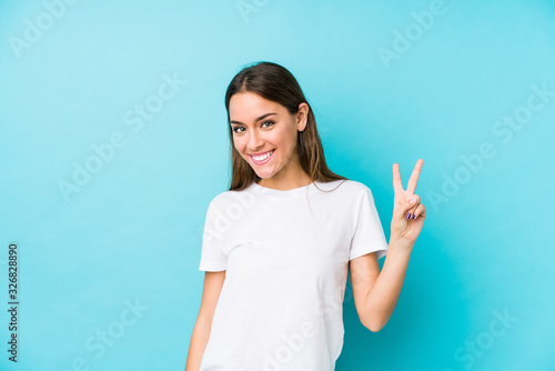 Young caucasian woman  isolated showing victory sign and smiling broadly.
