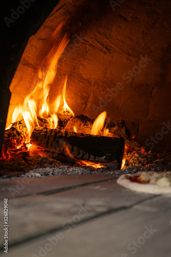 Pizza oven with pizza cooking inside large flames