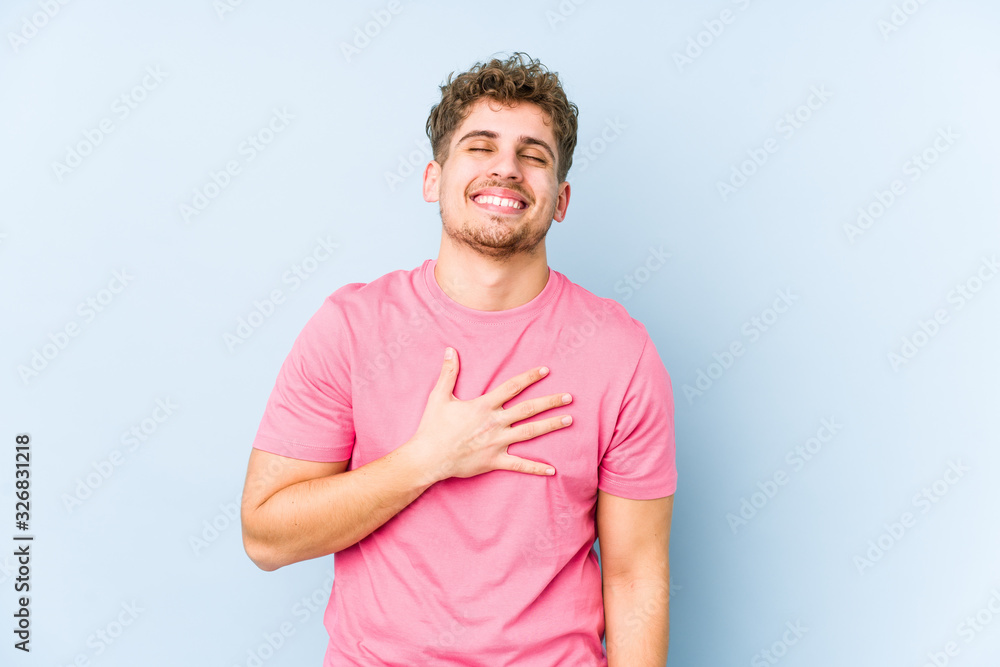Young blond curly hair caucasian man isolated laughs out loudly keeping hand on chest. Young blond curly hair caucasian man isolated laughs out loudly keeping hand on chest.