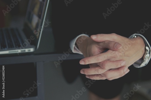 A businessman dressed in a suit sits at a desk with his hands clasped showing power and confidence.