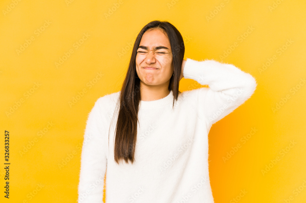 Fototapeta premium Young woman isolated on a yellow background suffering neck pain due to sedentary lifestyle.