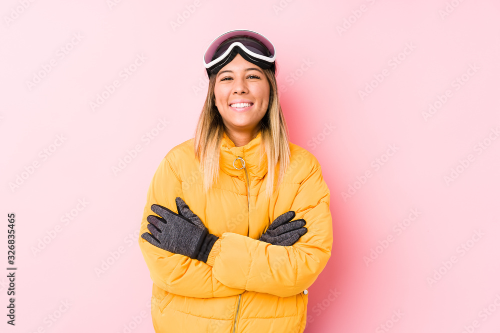 Fototapeta premium Young caucasian woman wearing a ski clothes in a pink background laughing and having fun.