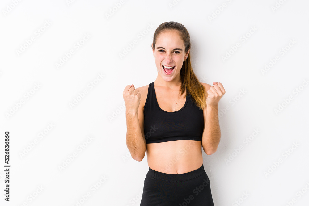 Young caucasian fitness woman posing in a white background cheering carefree and excited. Victory concept. Young caucasian fitness woman posing in a white background cheering carefree and excited. Victory concept.
