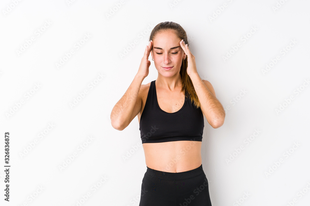 Young caucasian fitness woman posing in a white background touching temples and having headache. Young caucasian fitness woman posing in a white background touching temples and having headache.