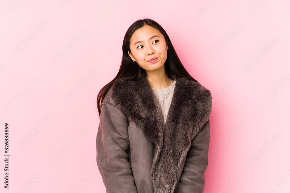 Young chinese woman wearing a coat isolated dreaming of achieving goals and purposes Young chinese woman wearing a coat isolated dreaming of achieving goals and purposes