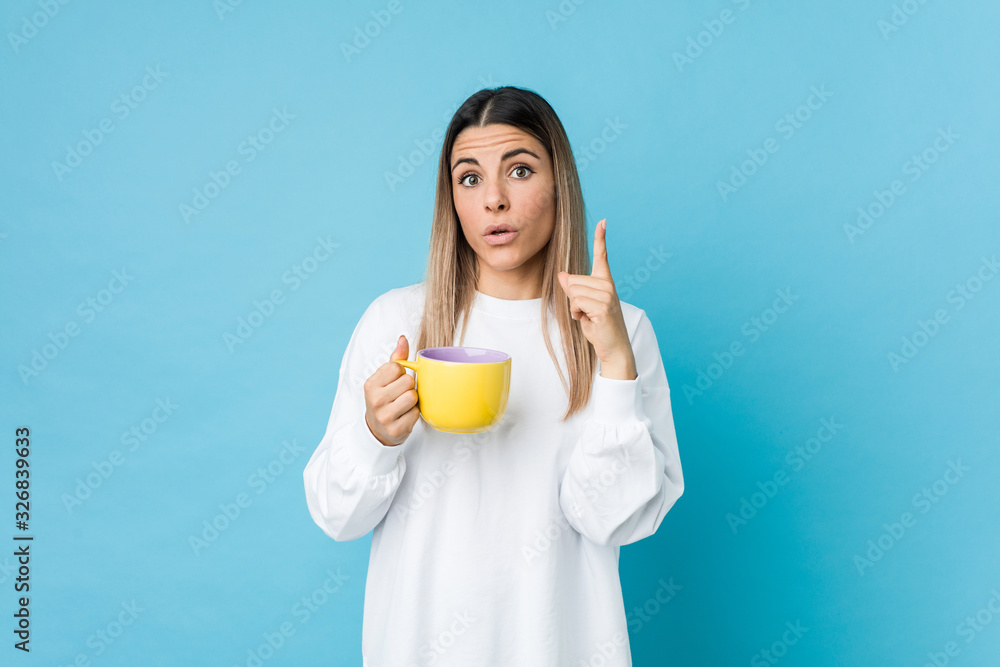 Young caucasian woman holding a coffee cup having some great idea, concept of creativity. Young caucasian woman holding a coffee cup having some great idea, concept of creativity.