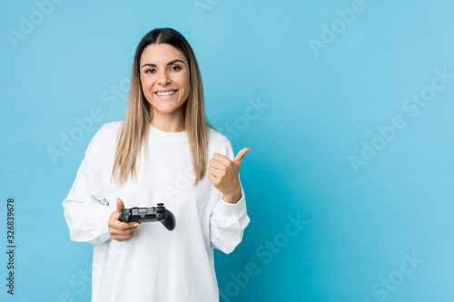Young caucasian woman holding a game controller smiling and raising thumb up