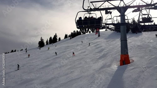 Riding a skilift on a beautiful cloudy and cold day in the alps. Skier are passing under the lift photo