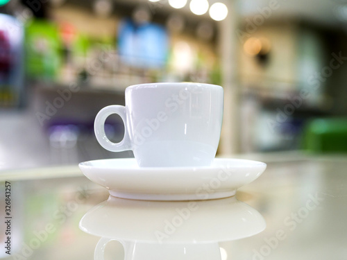 White little cup of espresso coffee on a table in a cafe. Defocused room