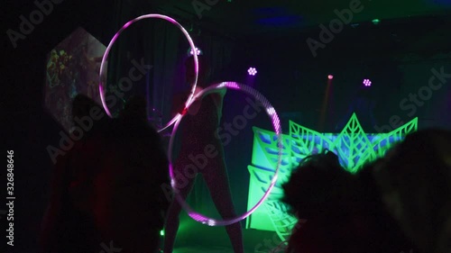 Performer in costume spinning multiple colorful hula hoops in front of a crowd - shot on RED