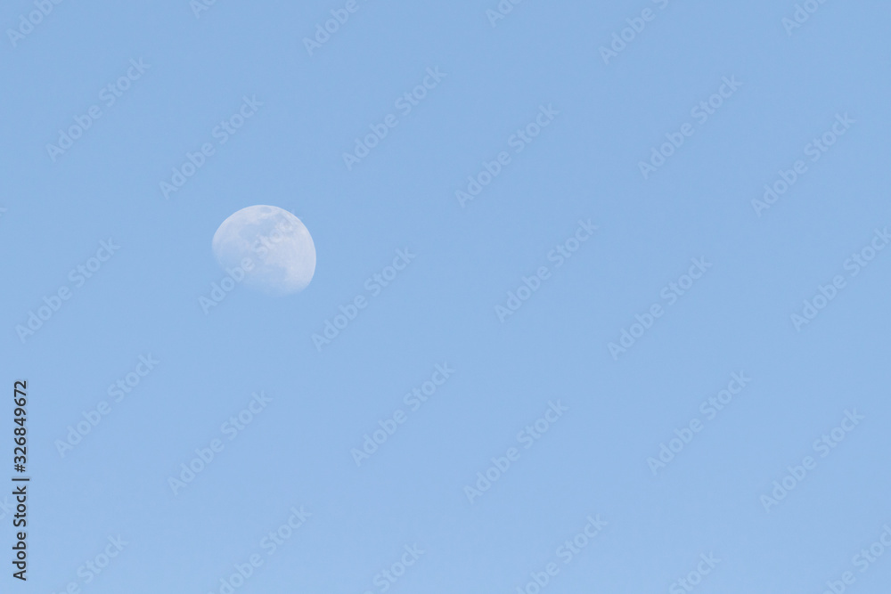 The moon against the blue sky day. The moon against the blue sky day.