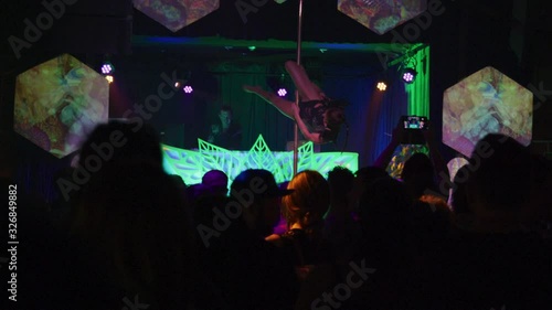 Stripper dancing on a strip pole in front of a crowd at a dance club - Wide Shot - shot on RED