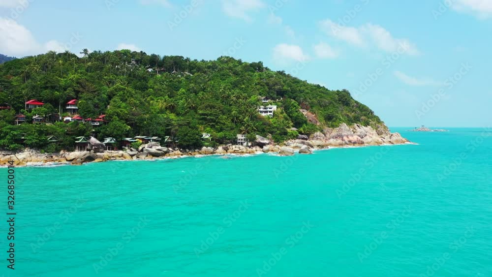 Round island in the turquoise calm waters with colorful bungalows between palms Round island in the turquoise calm waters with colorful bungalows between palms