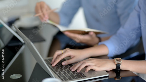 Cropped shot of female worker typing on laptop computer in simple co-working space
