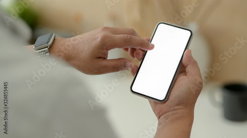 Close up view of male designer using blank screen smartphone while relaxed from work