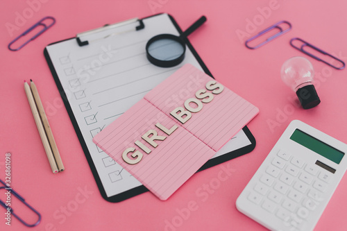 equal opportunities Girl Boss text on top of pink notebook on business office desk with to do list and mixed stationery on pink background