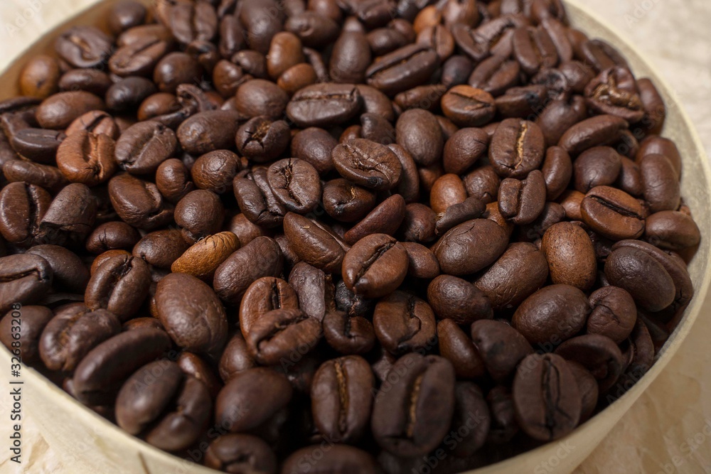 coffee grains in a round wooden jar on a background of crumpled parchment coffee grains in a round wooden jar on a background of crumpled parchment