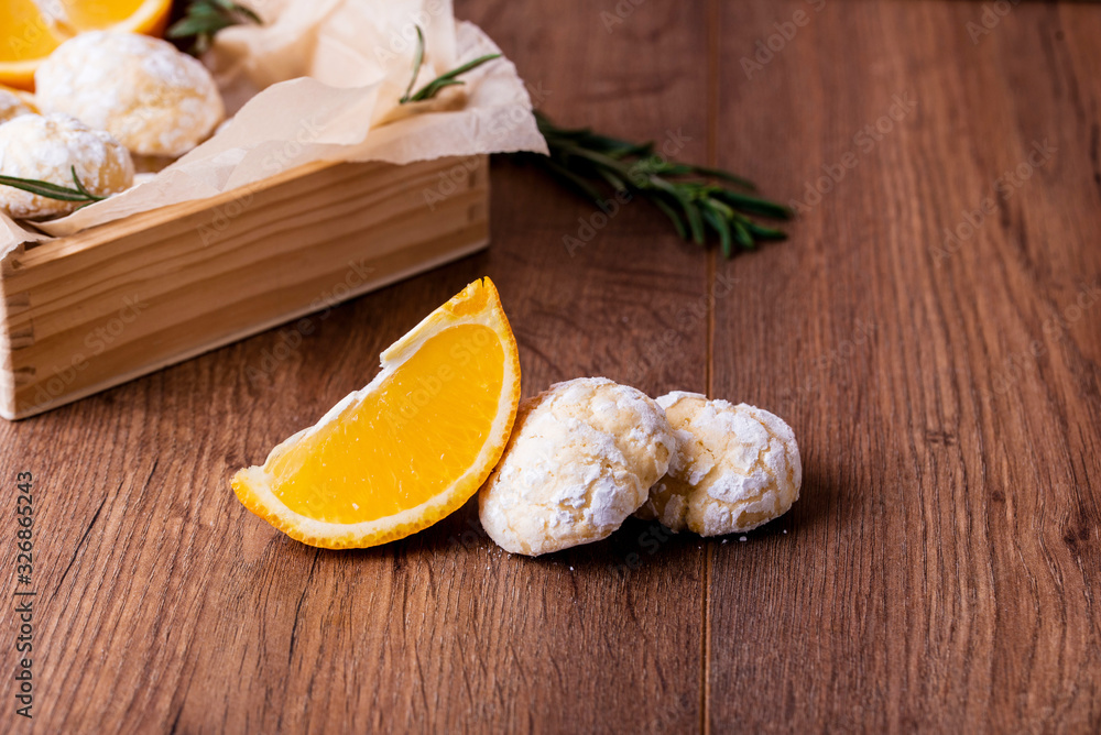 Shortbread orange biscuits with sprigs of semarin, with fresh orange and juice on the table.