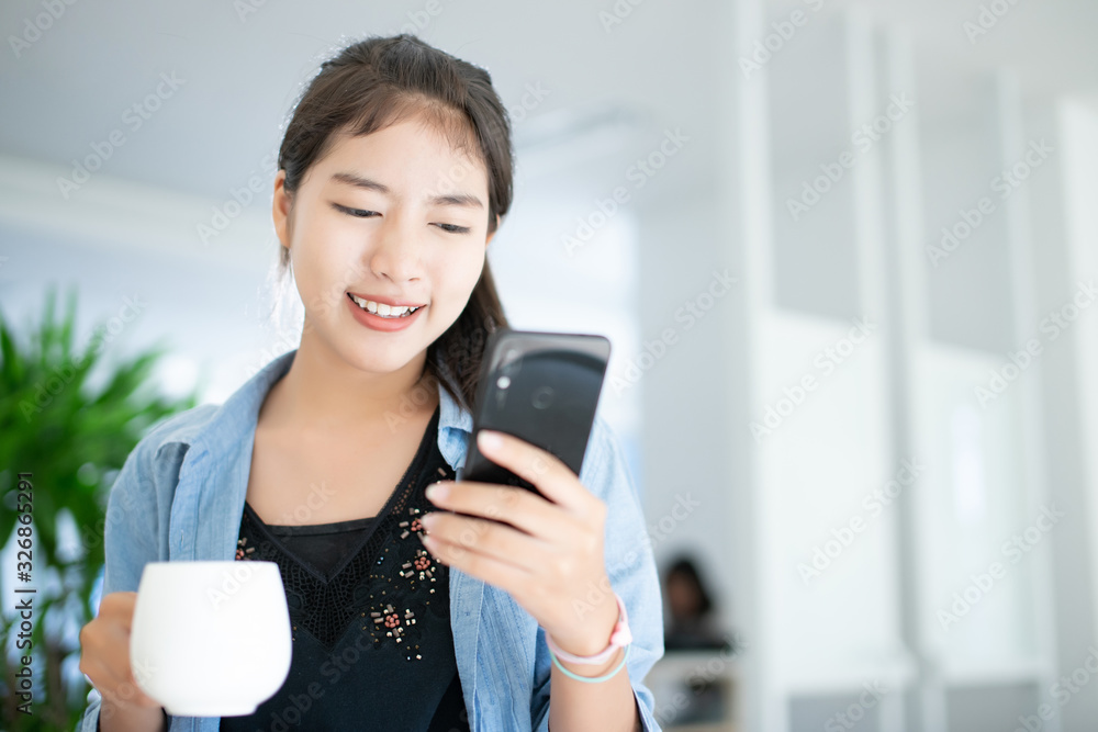Asian woman owner small business at home check stock package box by mobile phone before send to customer, happiness working concept. S Asian woman owner small business at home check stock package box by mobile phone before send to customer, happiness working concept. S