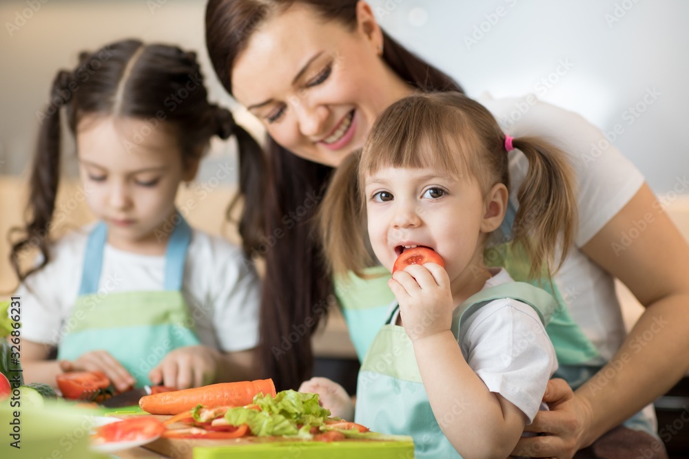 Positive woman and her kids preparing lunch in the kitchen