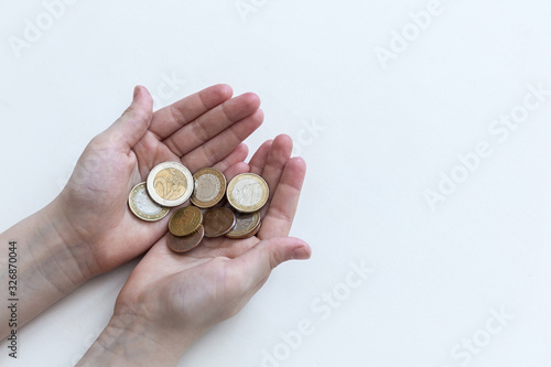 A handful of coins in the palm of hands. Euro coins on a white background