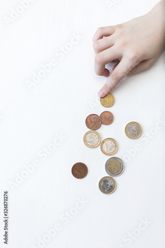 a child s hand counts Euro coins on a white background. The child saves money on the concept of the future