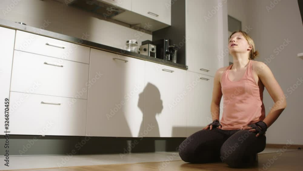 Young sporty caucasian woman stretching in on the kitchen floor. Practicing yoga at home, meditation and stress relief Young sporty caucasian woman stretching in on the kitchen floor. Practicing yoga at home, meditation and stress relief
