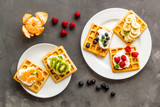 Belgian waffles with creamy cheese and berries on grey background top-down