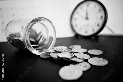 The clear bottle used to put coins fell on the floor and there were coins that fell out of the bottle.  Black and white photos related to finance.