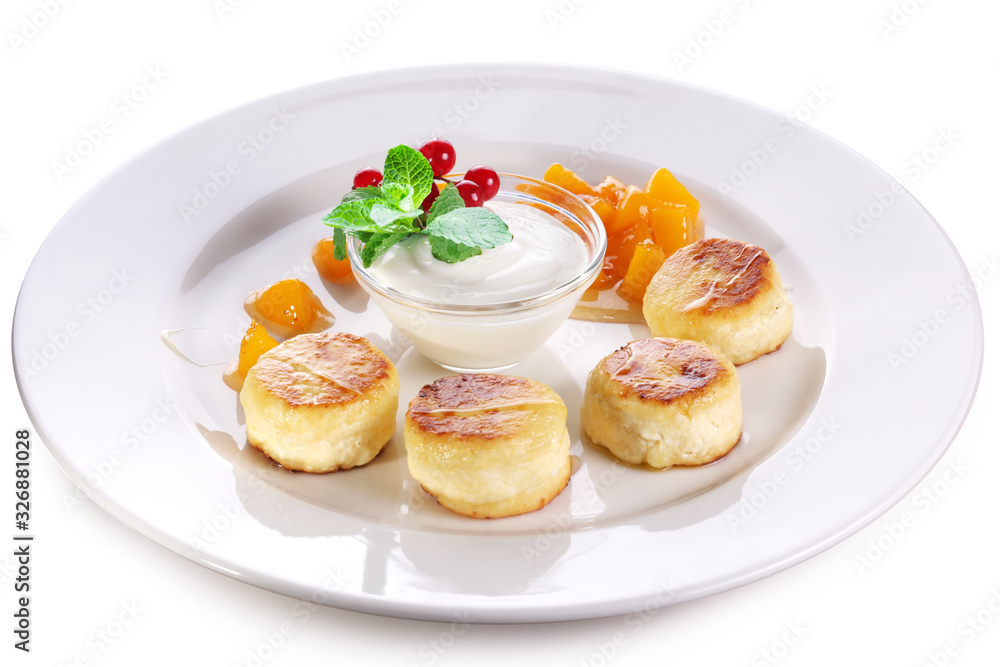 Cheese cakes with sour cream, slices of sweet peach, mint and red currants on a white plate. Clipping path. Cheese cakes with sour cream, slices of sweet peach, mint and red currants on a white plate. Clipping path.
