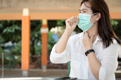 Sick asian female people with cold,flu,woman wearing hygienic mask and touch the neck with fever,cough,sore throat or Corona virus Covid-19 symptoms,feel unwell, ill,medical treatment,healthcare.