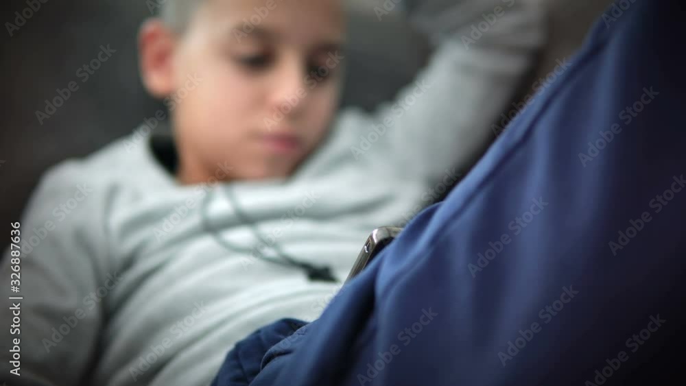 Cute little boy watching cartoons on smart phone at home on the sofa Cute little boy watching cartoons on smart phone at home on the sofa