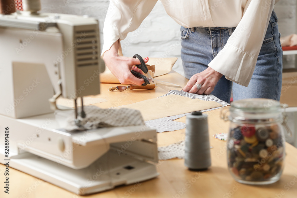 Seamstress cutting fabric with scissors. Fashion designer working with fabric in fashion studio. Seamstress cutting fabric with scissors. Fashion designer working with fabric in fashion studio.
