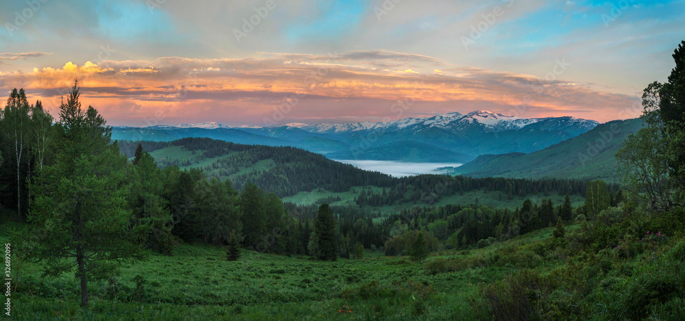 Sunset sky over the Siberian expanses. Snow-capped peaks, taiga forest.