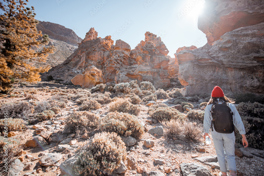 Young female traveler walking on the rocky terrain between huge rocks volcanic origin during a sunny day. Traveling on Tenerife island, Spain Young female traveler walking on the rocky terrain between huge rocks volcanic origin during a sunny day. Traveling on Tenerife island, Spain