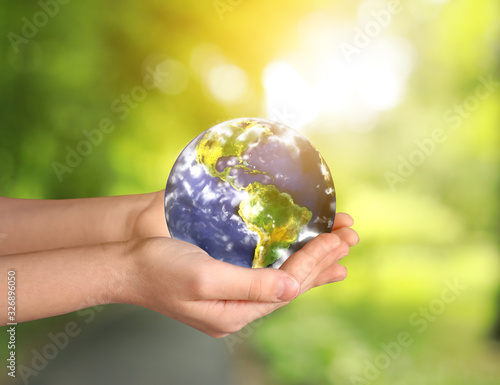 Fototapeta Naklejka Na Ścianę i Meble -  Hands of little child with planet on blurred background. Earth Day celebration