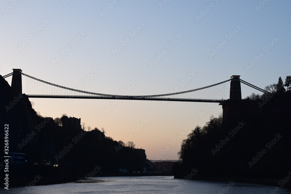 Obraz premium Silhouetted bridge over a river at sunset