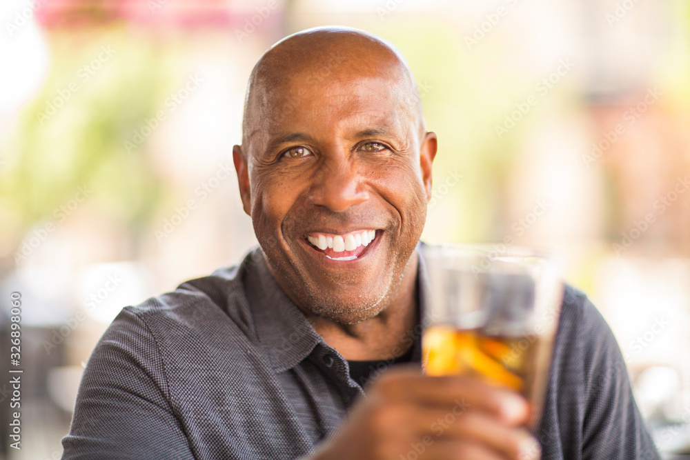 Mature African American man drinking at a restaurant. Mature African American man drinking at a restaurant.