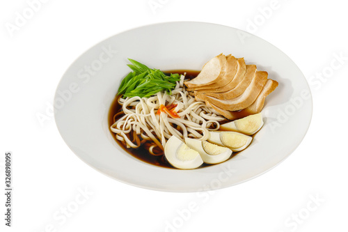 fo bo soup, with vegetables, noodles, greens onions, egg, chicken, spicy red sauce in a white plate isolated white. Serving dishes in a cafe, restaurant, for a menu, Side view photo