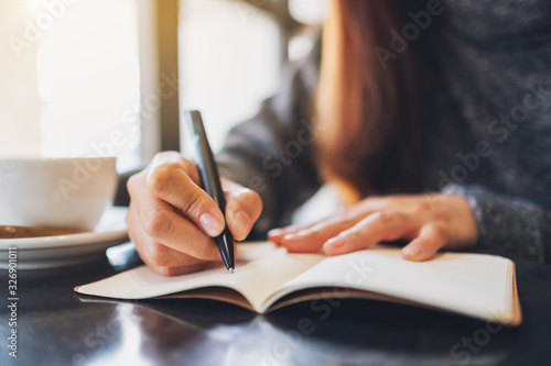 Closeup image of a woman writing on a blank notebook on the table