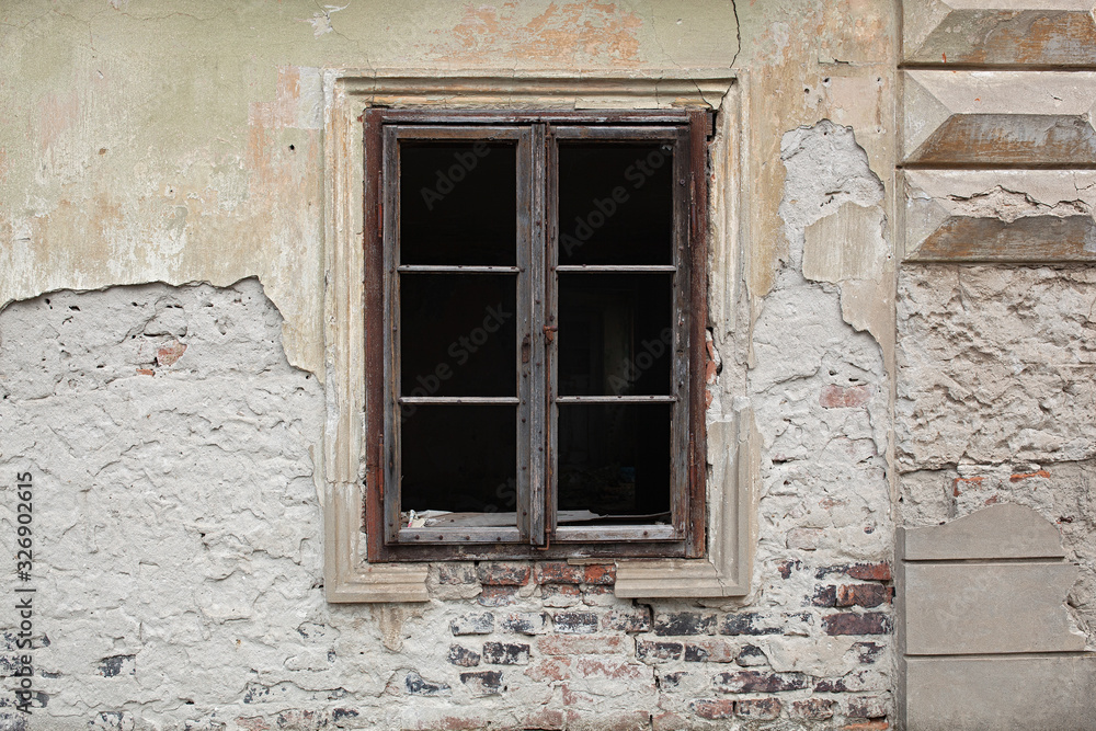 Old wooden window, no glass, just frame on an old abandoned building with weathered facade Old wooden window, no glass, just frame on an old abandoned building with weathered facade